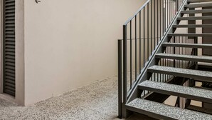 A staircase with metal railings and a speckled floor, leading to a door labeled '01' on a plain wall. - El Pocito By Homirent  (San José de los Olvera)