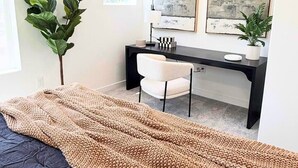 Een moderne slaapkamer met een bed, een bureau en twee afbeeldingen in lijsten aan de muur.
