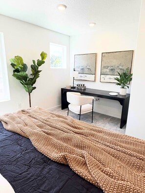 Ein modernes Schlafzimmer mit einem Bett, einem Schreibtisch und zwei gerahmten Bildern an der Wand.