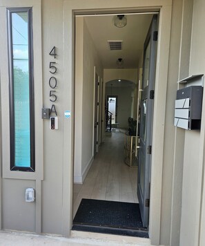 A hallway with a door labeled '4505A,' a security keypad, a doormat, and a potted plant. - Modern 4BR New Home - Minutes to NRG, Med. Ctr, Downtown & UH (Houston)
