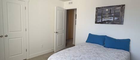 Un dormitorio con cama, una puerta, un pasillo y un cuadro colgado en la pared.