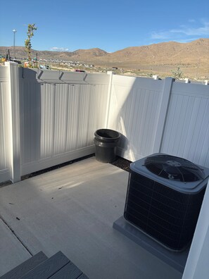 A rooftop patio with a white fence, a black trash bin, and an air conditioning unit. - New townhome in peaceful- friendly neighborhood with 3 bedrooms and 2.1/2 bath (Eagle Mountain)