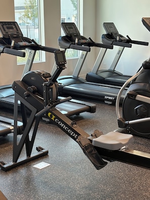 A gym with stationary bikes and treadmills, a window with a view of the outside, and a speckled floor. - New townhome in peaceful- friendly neighborhood with 3 bedrooms and 2.1/2 bath (Eagle Mountain)