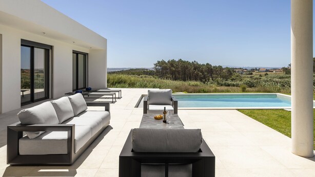 Ein moderner Außenbereich mit Sitzgelegenheiten, einem Pool, großen Fenstern und Blick auf die Landschaft.
