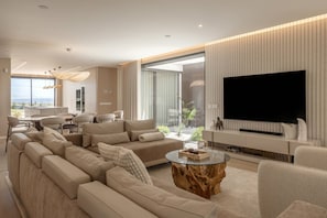 Ein modernes Wohnzimmer mit einem Ecksofa, einem Glastisch und einem Flachbildfernseher.