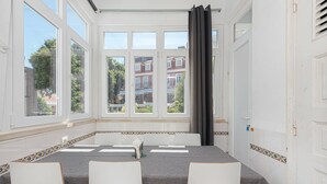Ett konferensrum med ett stort fönster, ett bord med stolar och utsikt över byggnaderna utanför.