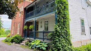 Una casa de dos pisos con balcón, fachada de ladrillo y exterior blanco.