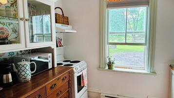 Una cocina con estufa, microondas y armarios de madera.