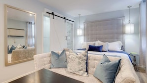 Een moderne slaapkamer met een groot bed, een bank, een spiegel en een hanglamp.