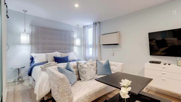 Een moderne slaapkamer met een bed, een bank, een televisie en een klein tafeltje.