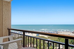 Ein Balkon mit Blick auf einen Strand, Palmen und einen klaren Himmel.