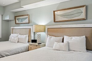 A hotel room with two beds, a nightstand, a lamp, and framed artwork on the walls. - Beach Cove Resort 515 Oceanfront Condo (North Myrtle Beach)
