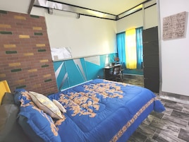 Un dormitorio con cama, escritorio, silla y espejo.