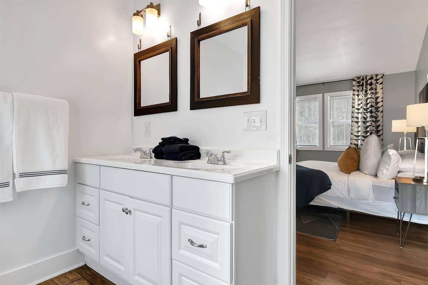 Une salle de bain avec un meuble-lavabo blanc, deux miroirs et un évier.