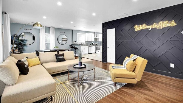 A modern living room with a sofa, armchair, and a decorative wall with 'Welcome to Atlanta' sign. - Beautiful Den 4Bd 4bth Perfect for Longer Stays (Atlanta)