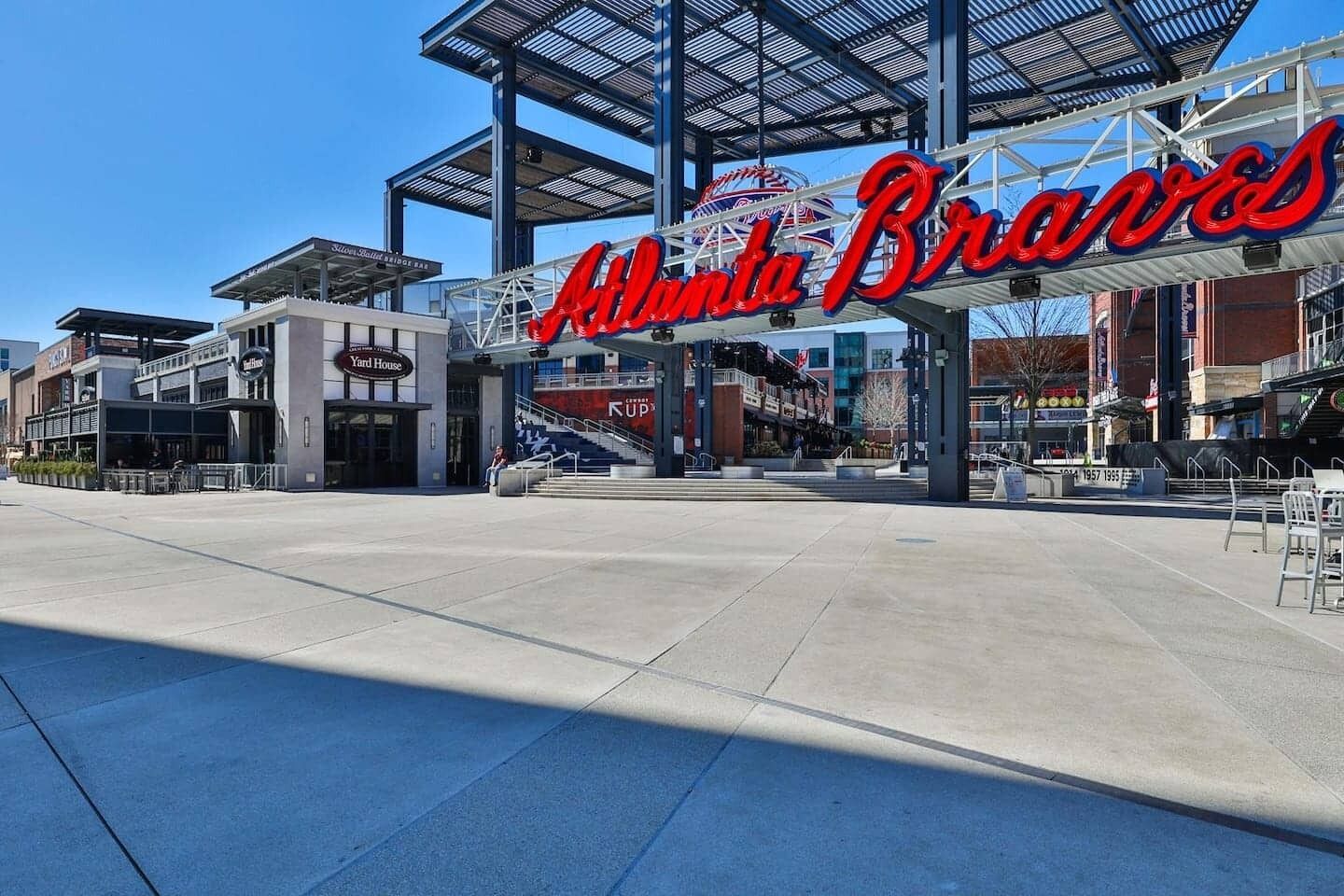 Un espacio al aire libre con un gran cartel de los Bravos de Atlanta, una galería techada y un edificio que dice 'Yard House'.