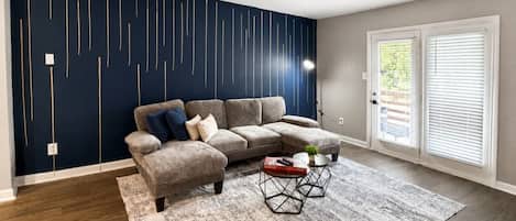 A living room with a sectional sofa, a coffee table, and a patterned rug.