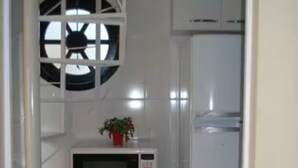 Una cocina compacta con microondas, refrigerador y un mueble pequeño.