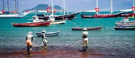 Un port où se trouvent de nombreux bateaux et où des personnes pratiquent la pêche.