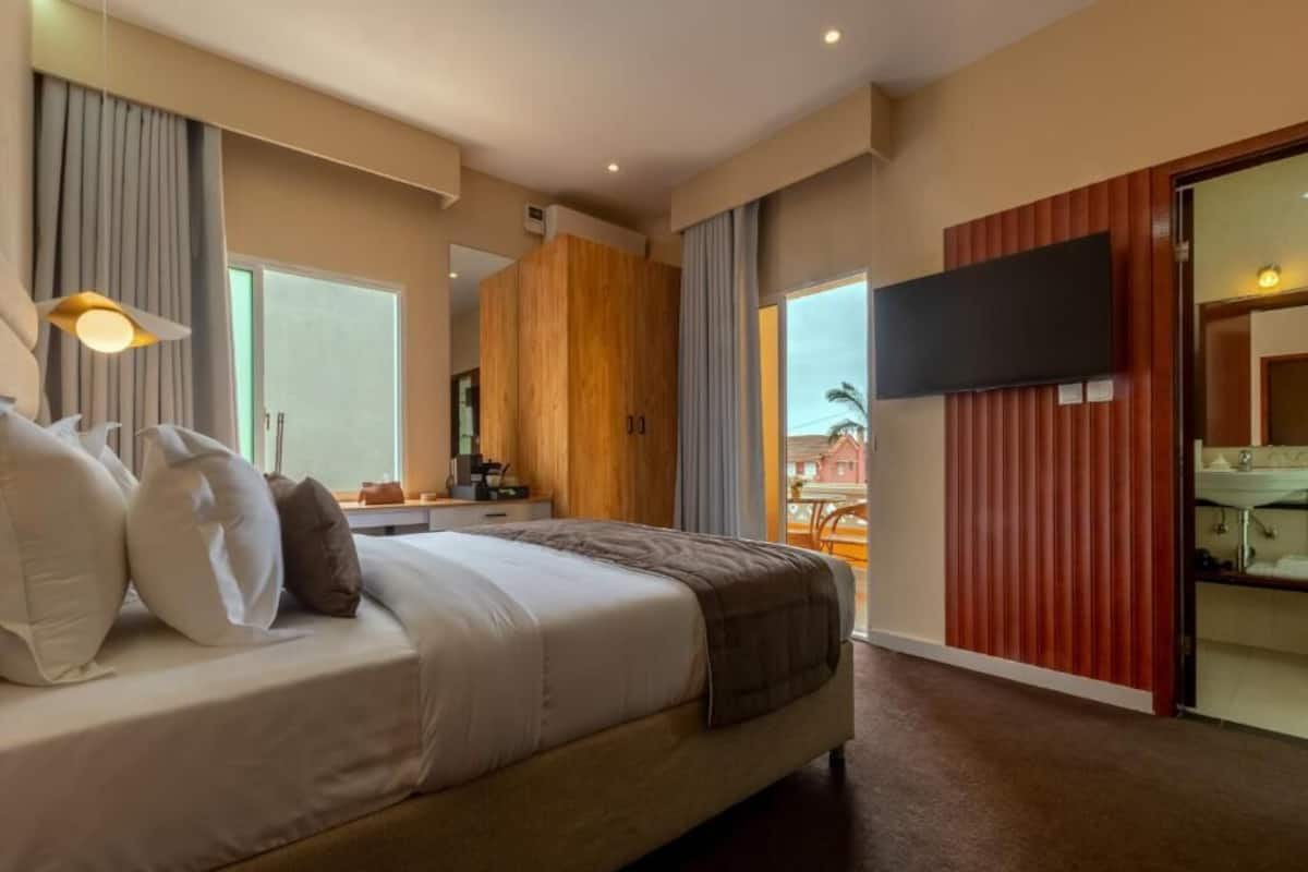 Habitación de hotel con cama, televisión, escritorio y vistas al exterior.