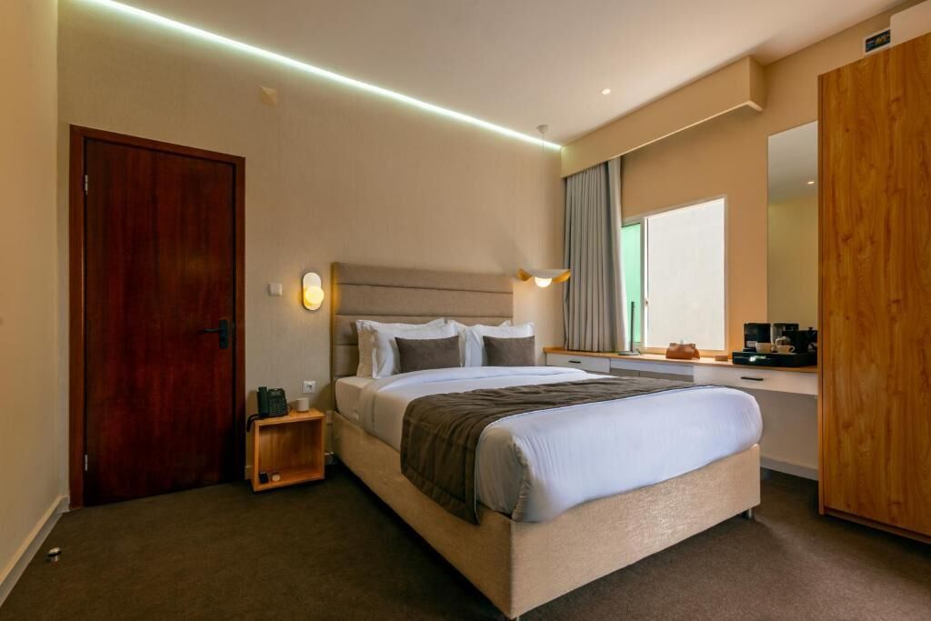 Una habitación de hotel con cama, mesita de noche, lámpara y espejo.