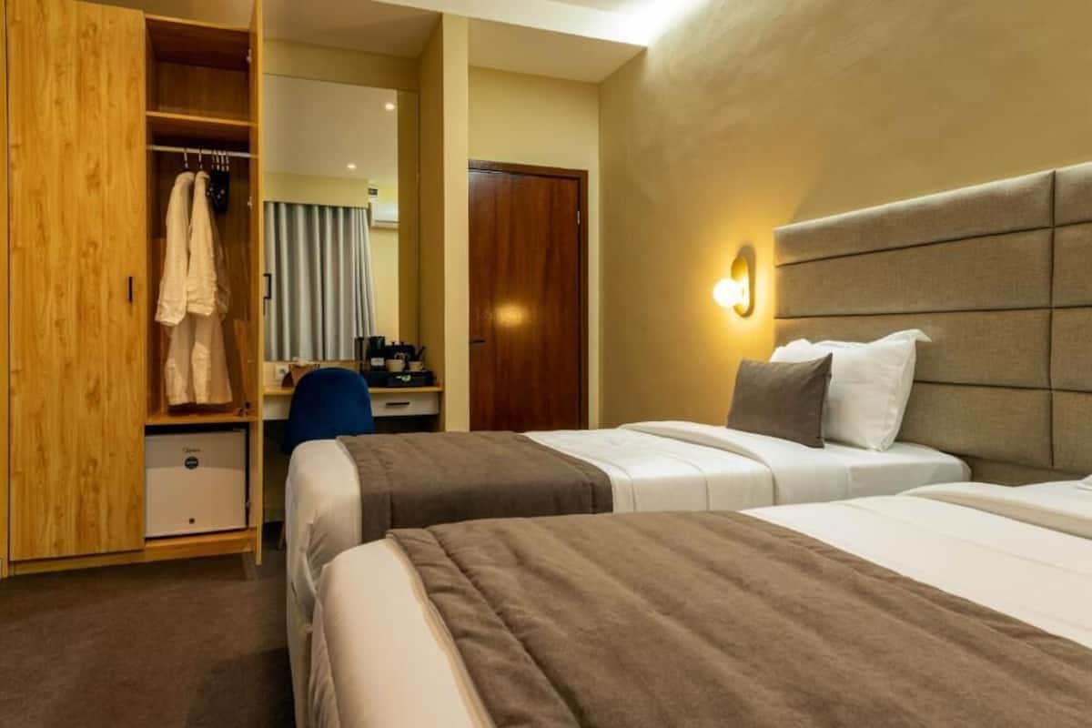 Habitación con 2 camas individuales | Espacio para trabajar con laptop y tabla de planchar con plancha