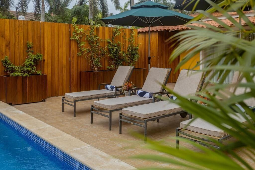 A poolside area with lounge chairs and a wooden fence.