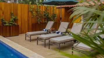 Zona junto a la piscina con sillas de descanso y una valla de madera.