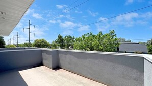 Eine Dachterrasse mit Betonboden, einer niedrigen Mauer und wolkenlosem, blauem Himmel.