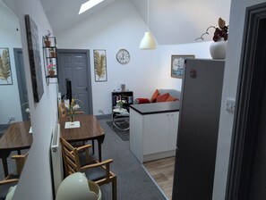Un espacio habitable compacto con comedor, kitchenette y una pequeña zona de estar.
