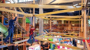 Zona de juegos interior con una estructura de escalada y un tobogán.