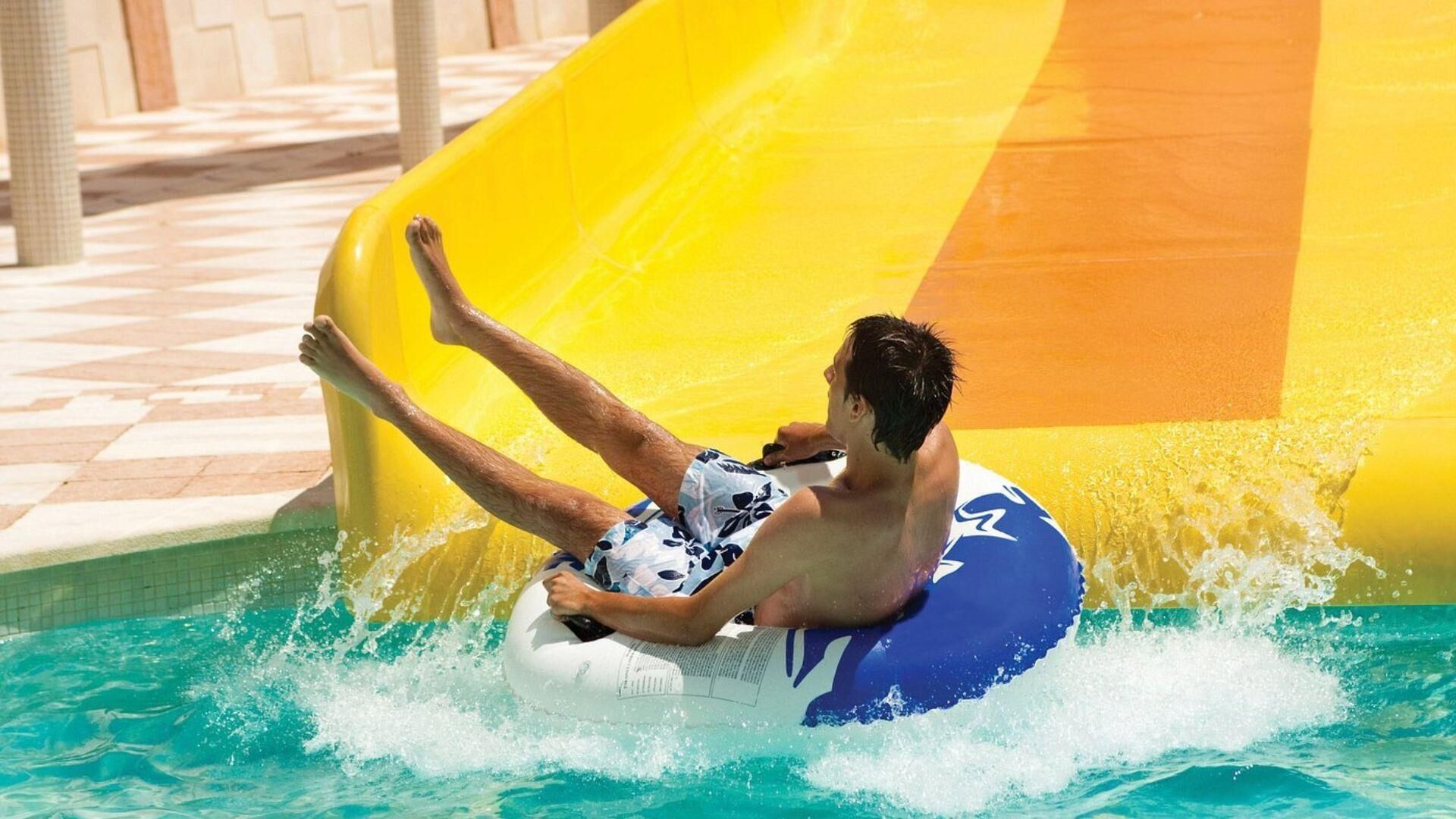 Una persona su uno scivolo acquatico in un’area piscina.
