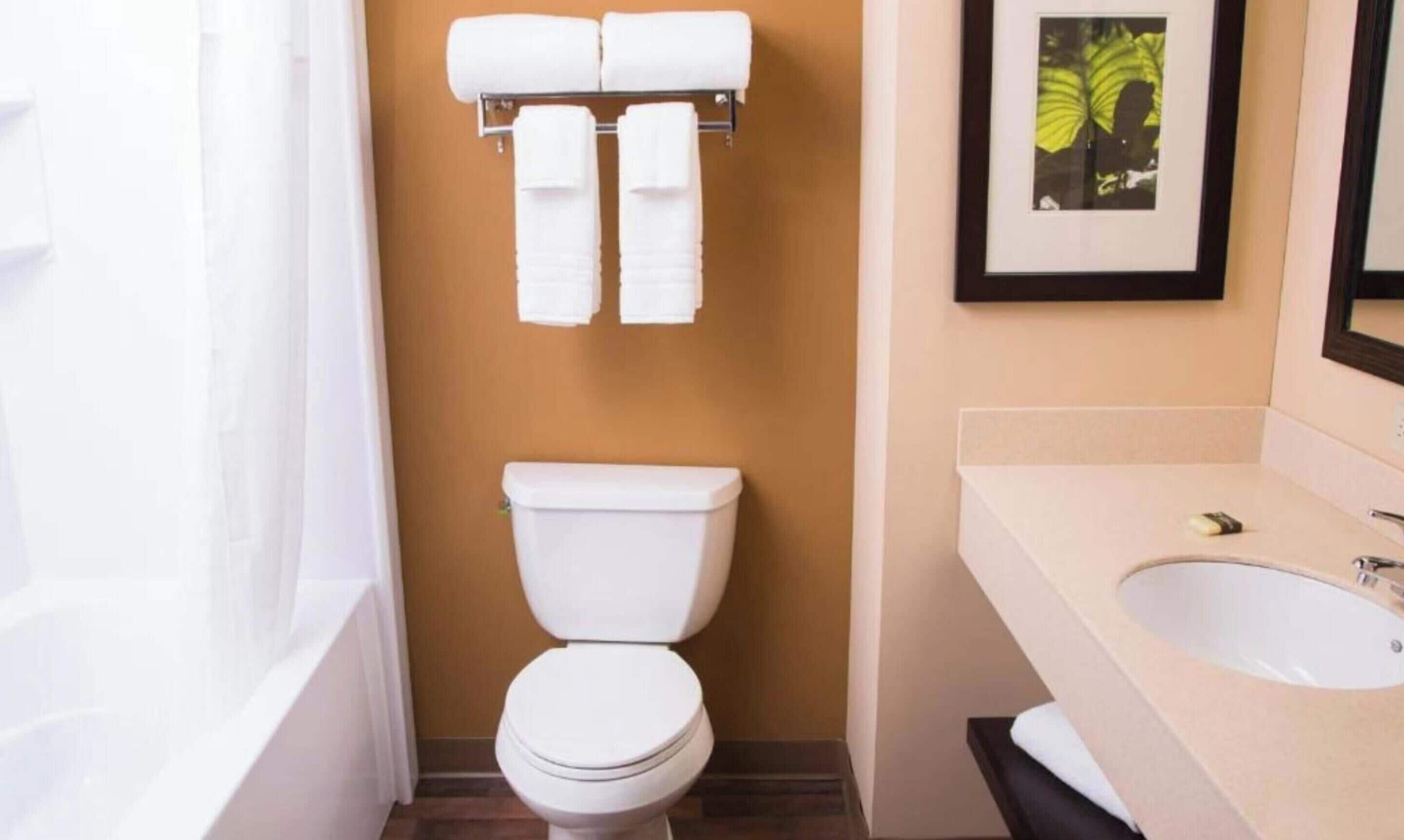 Une salle de bain équipée de toilettes, d’un lavabo et d’un porte-serviettes avec des serviettes.