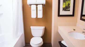 A bathroom with a toilet, a sink, and a towel rack with towels.