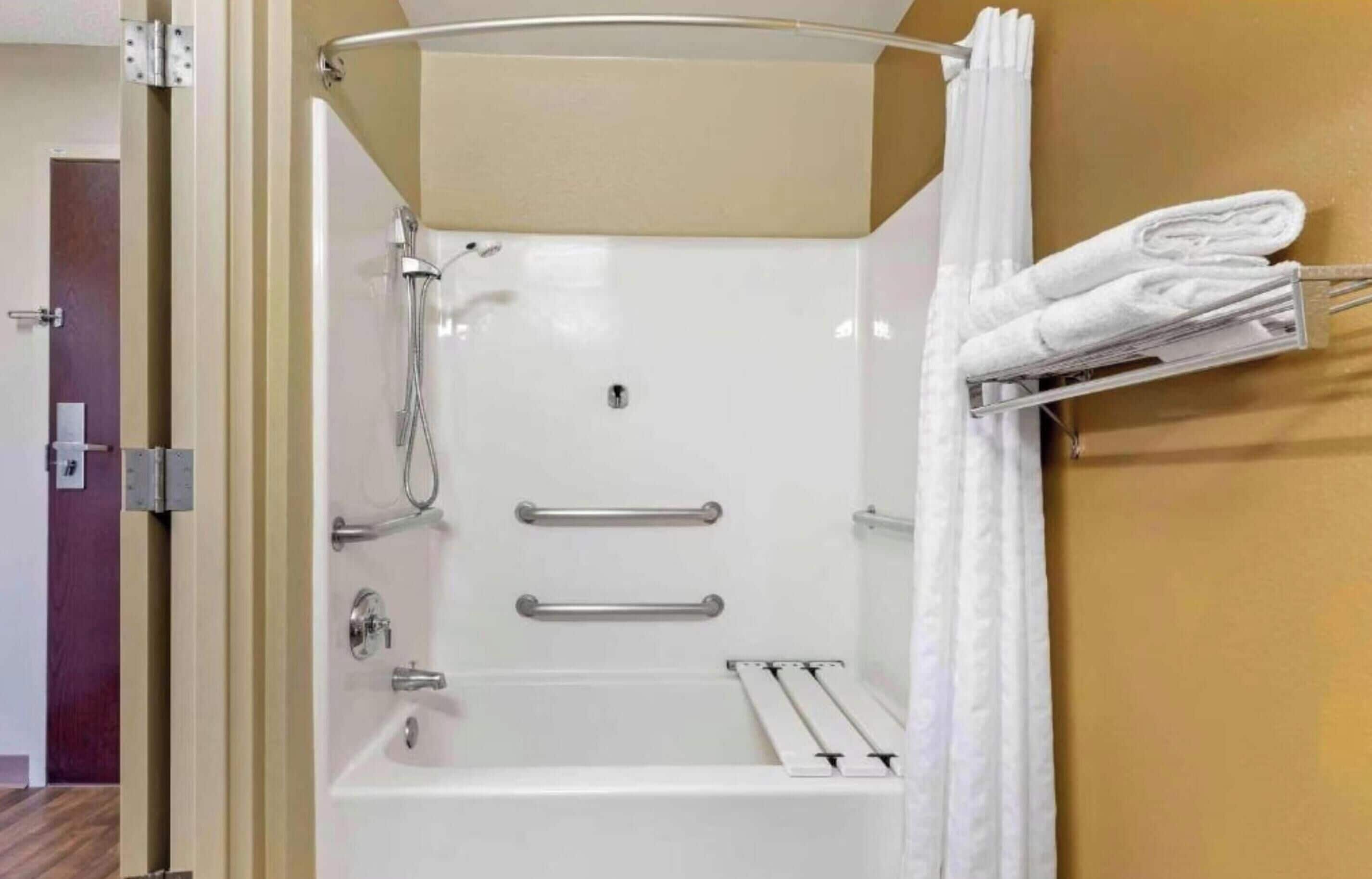 A bathroom with a bathtub, shower, towel rack, and a door.