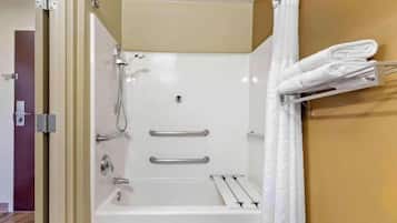 Baño con bañera, ducha, toallero y puerta.