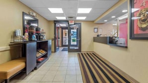 Un pasillo de hotel con un banco, una estación de café y una puerta de salida.