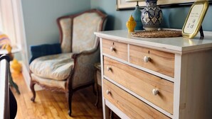 A wooden dresser with drawers, a lamp, and a framed picture on top.