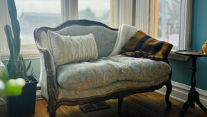 A vintage sofa with patterned cushions, a cactus plant, and a small table with a yellow object.