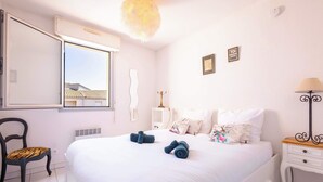 Une chambre d’hôtel avec un lit, une chaise, une table de chevet, une lampe et une fenêtre.