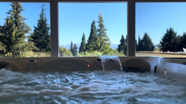 Ein Whirlpool mit auslaufendem Wasser, vor einer Kulisse aus Bäumen und blauem Himmel.