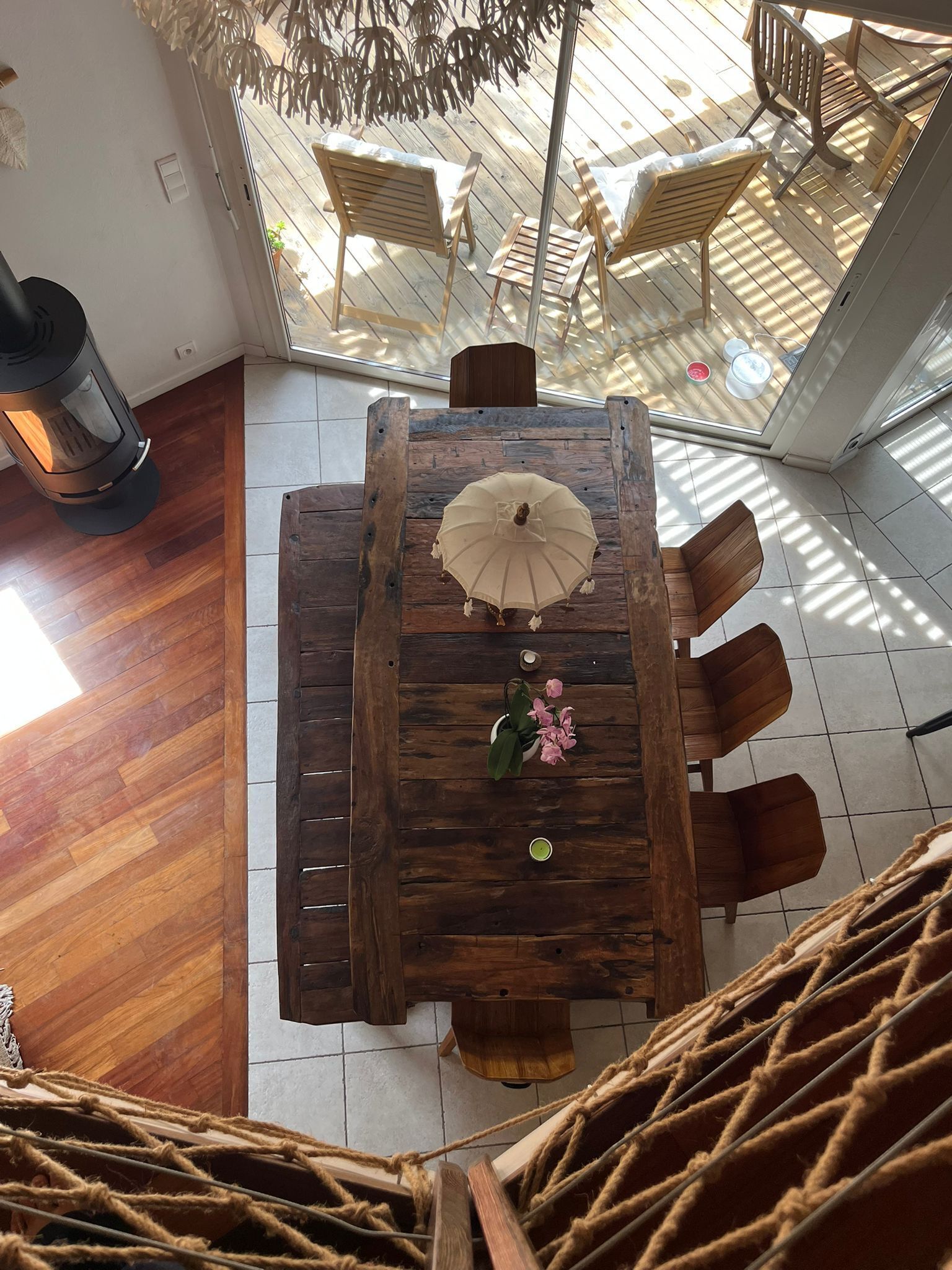 Une table à manger en bois avec des chaises, un parasol suspendu et une plante en pot.