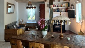 Een ruime woonruimte met een houten eettafel, stoelen, een bank en een trap met een touwbalustrade.