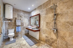 Un baño con inodoro, lavamanos, espejo, ducha y toallero.