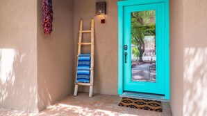 Uma porta azul-turquesa com uma escada de madeira e um tapete estampado.