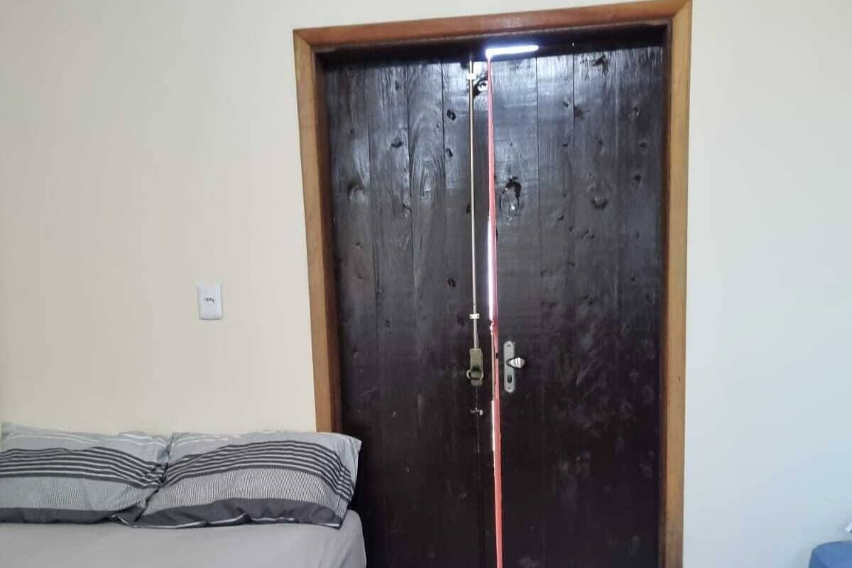 A bedroom with a bed, a wooden door, and a tiled floor.