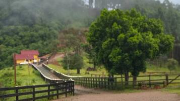 A gravel road with a wooden fence, a tree, and a distant building.