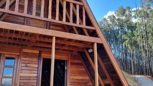 Uma cabana de madeira com telhado triangular, uma varanda e uma porta que dá para o interior.