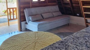 Um quarto aconchegante com um sofá cinza, um tapete tecido e uma escada de madeira.