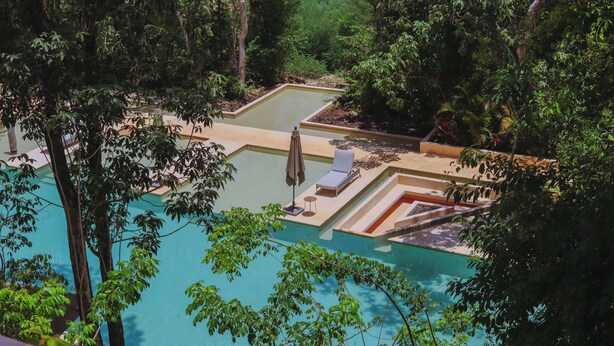 A pool with a sun lounger and a small table, surrounded by lush greenery. - Chic Jungle 1BR: Balcony Priv Pool, Steam & Gym (Tulum)